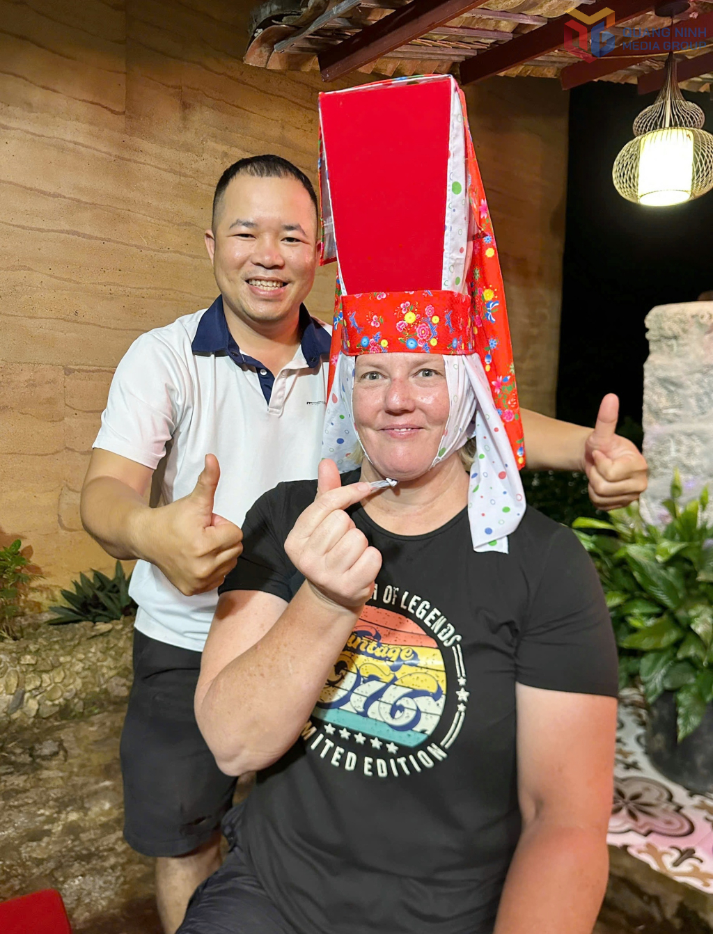Chị Kristy Shooter (du khách đến từ Australia) thử trải nghiệm đội mũ phụ nữ người Dao Thanh Phán trong chuyến du lịch tại các xã Bình Liêu, Lục Hồn và Hoành Mô tháng 7/2026.
